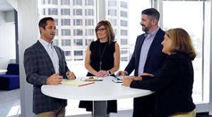 office professionals meeting around a table in training video for The Brooks Group