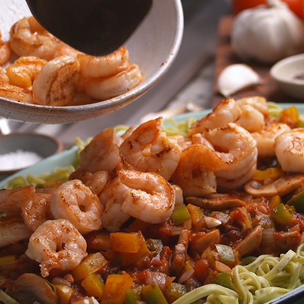 food photography shrimp being poured on pasta dish